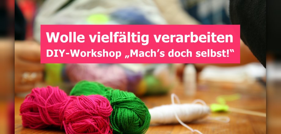 Das Bild zeigt eine Nahaufnahme von Garnknäueln in leuchtenden Farben (Pink, Grün, Weiß) auf einer Holzoberfläche. Darüber befindet sich ein rosafarbenes Textfeld mit der Aufschrift „Wolle vielfältig verarbeiten DIY-Workshop „Mach's doch selbst!"“. Der Hintergrund ist unscharf und deutet auf eine Bastel- oder Werkstattumgebung hin.